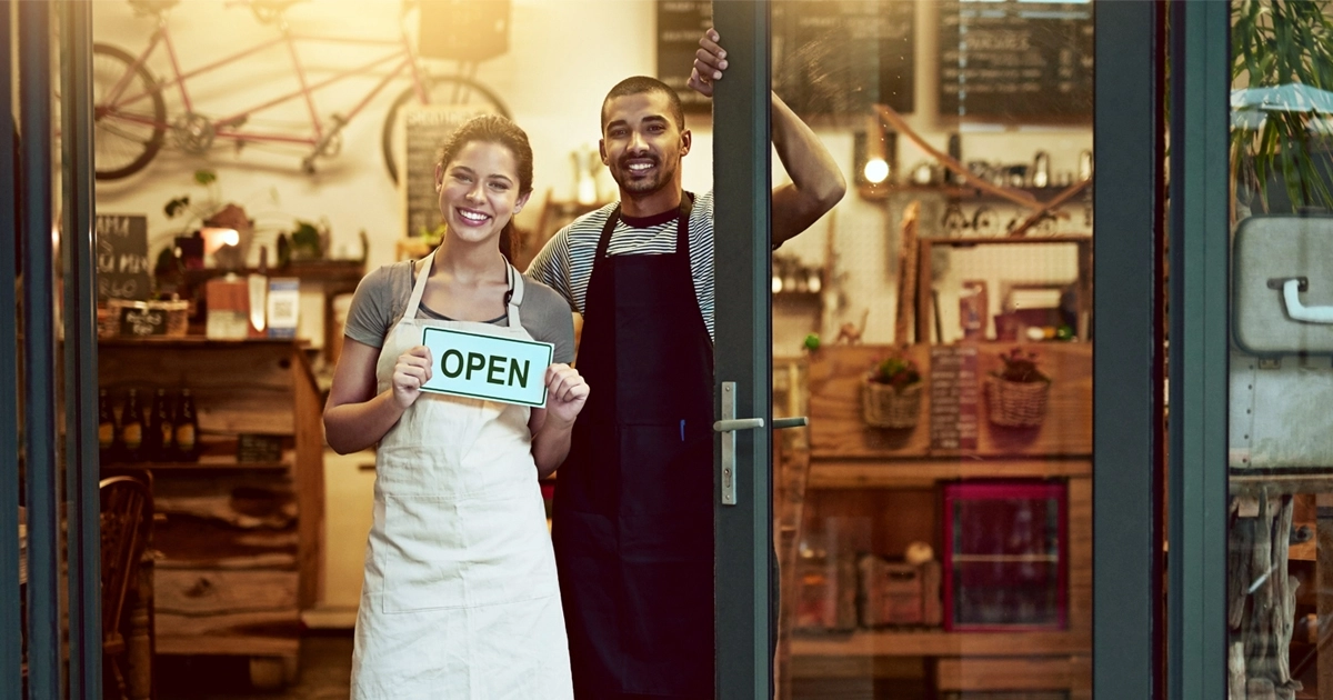 Store employees holding open sign