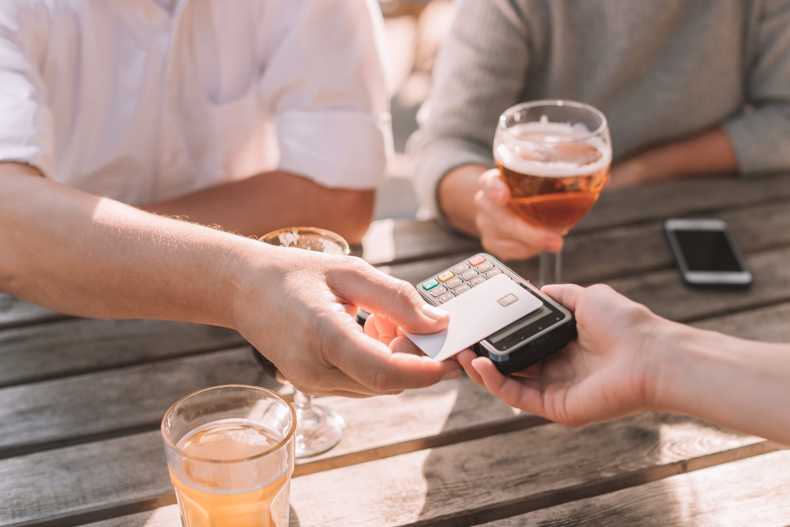 hombres pagando en cervecería con tarjeta de crédito