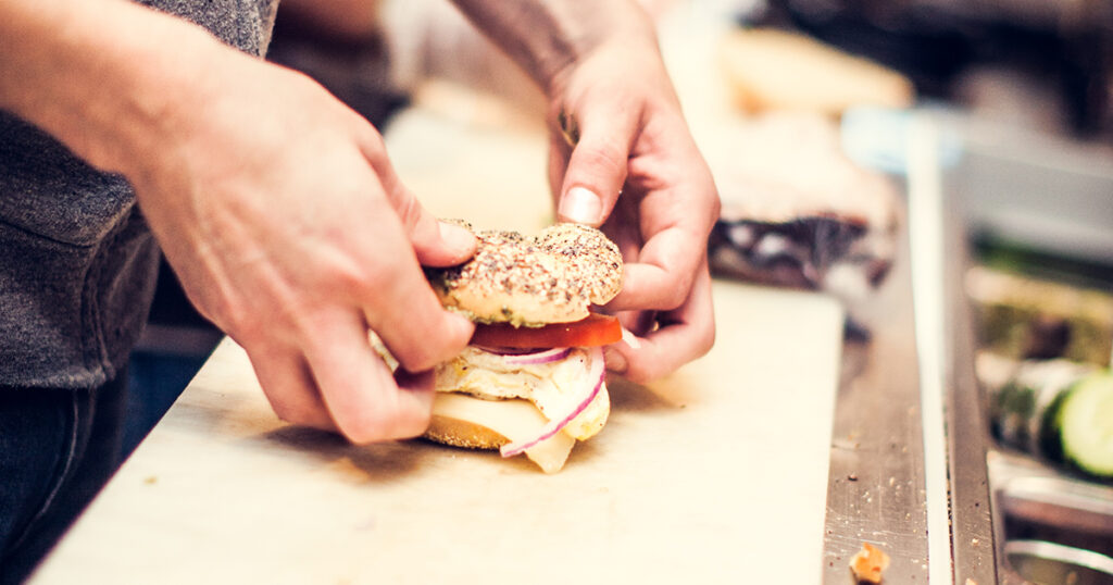 trabajador preparando un sándwich de bagel