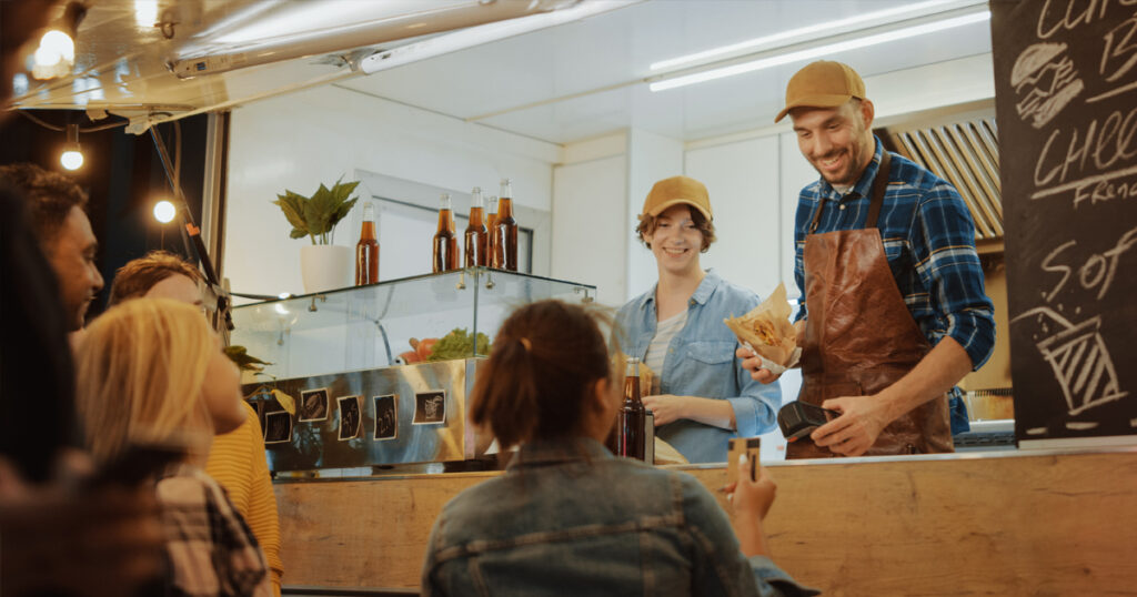 Clientes y propietarios interactuando en un camión de comida. 