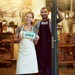 Store employees holding open sign